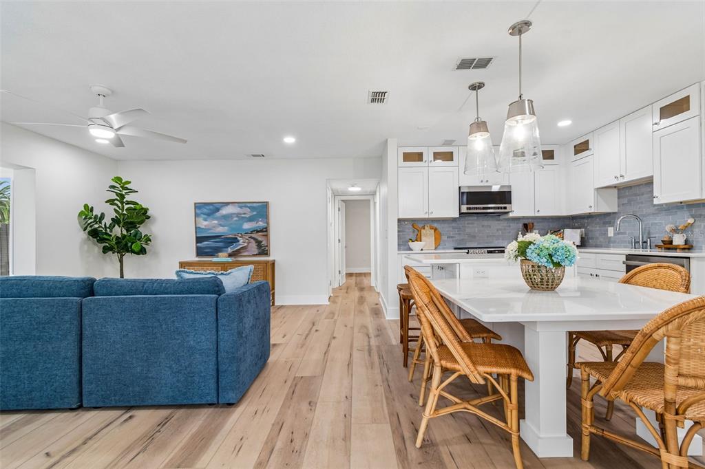 An open-concept kitchen and living area features white cabinetry, a kitchen island, and wood flooring — 403 DRIFTWOOD DRIVE W, PALM HARBOR, FL