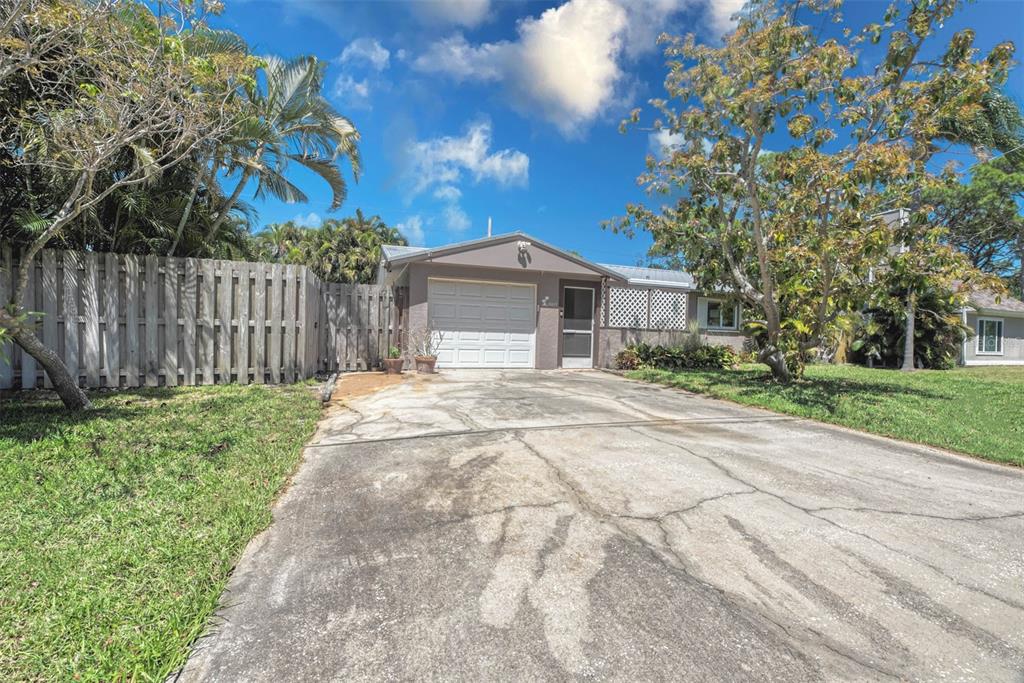 A single-story house with a white garage door, a concrete driveway, and a wooden fence — 3217 RESTFUL LANE, SARASOTA, FL
