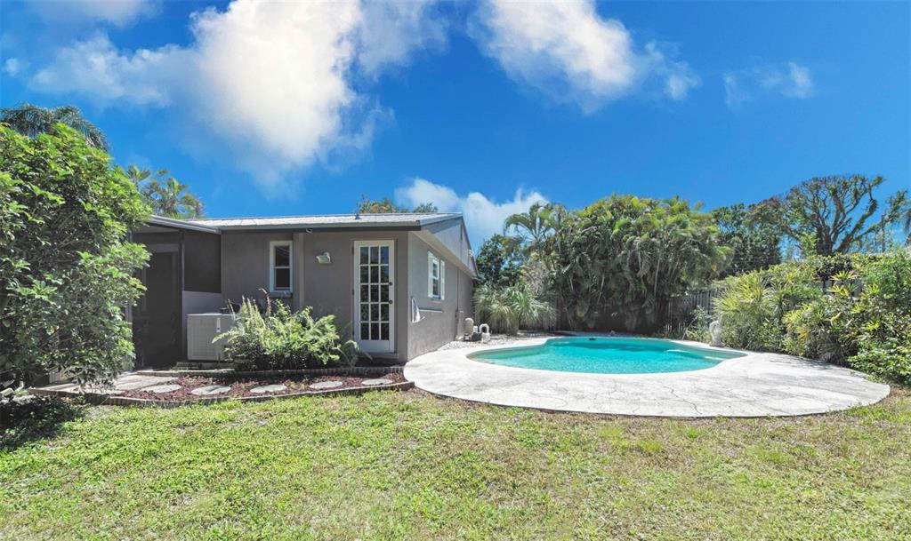 A backyard features a swimming pool with a concrete deck next to a gray house — 3217 RESTFUL LANE, SARASOTA, FL