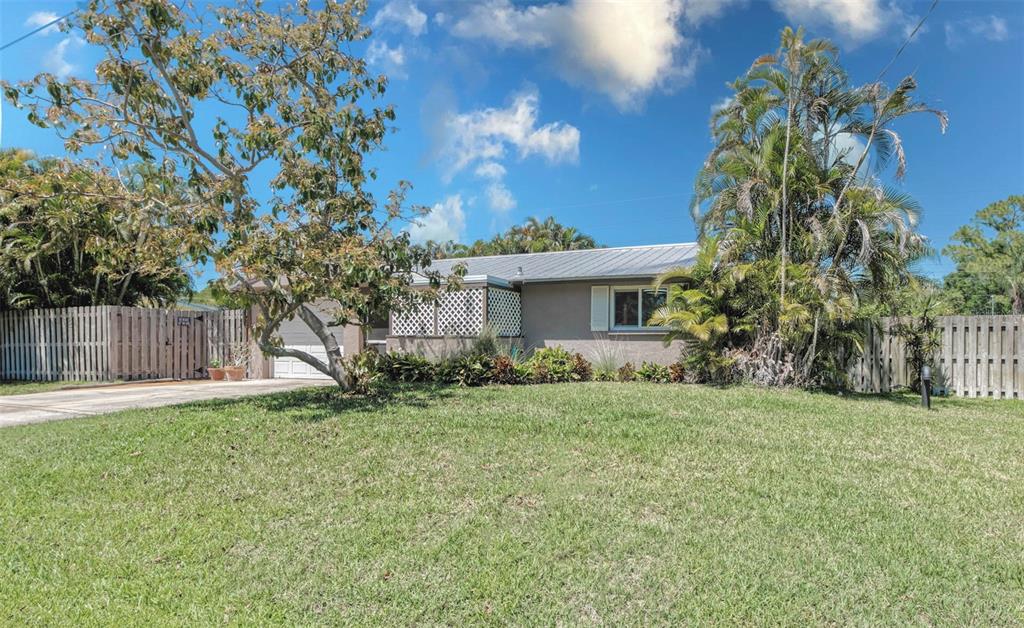 A single-story house with a metal roof, a front lawn, and palm trees — 3217 RESTFUL LANE, SARASOTA, FL