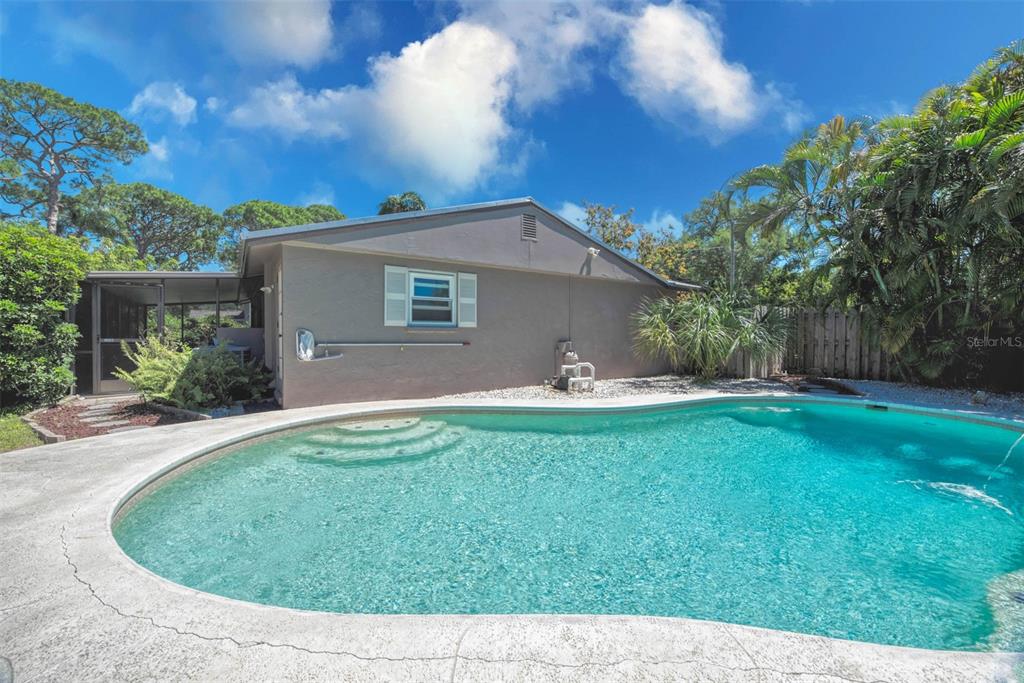 A backyard features a swimming pool with steps next to a house with a screened porch — 3217 RESTFUL LANE, SARASOTA, FL