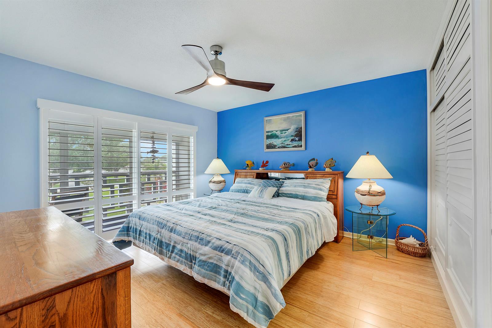 A bedroom features a blue accent wall, a bed with striped bedding, and wood flooring — 331 Tequesta Drive # 213, Tequesta FL 33469, TEQUESTA, FL