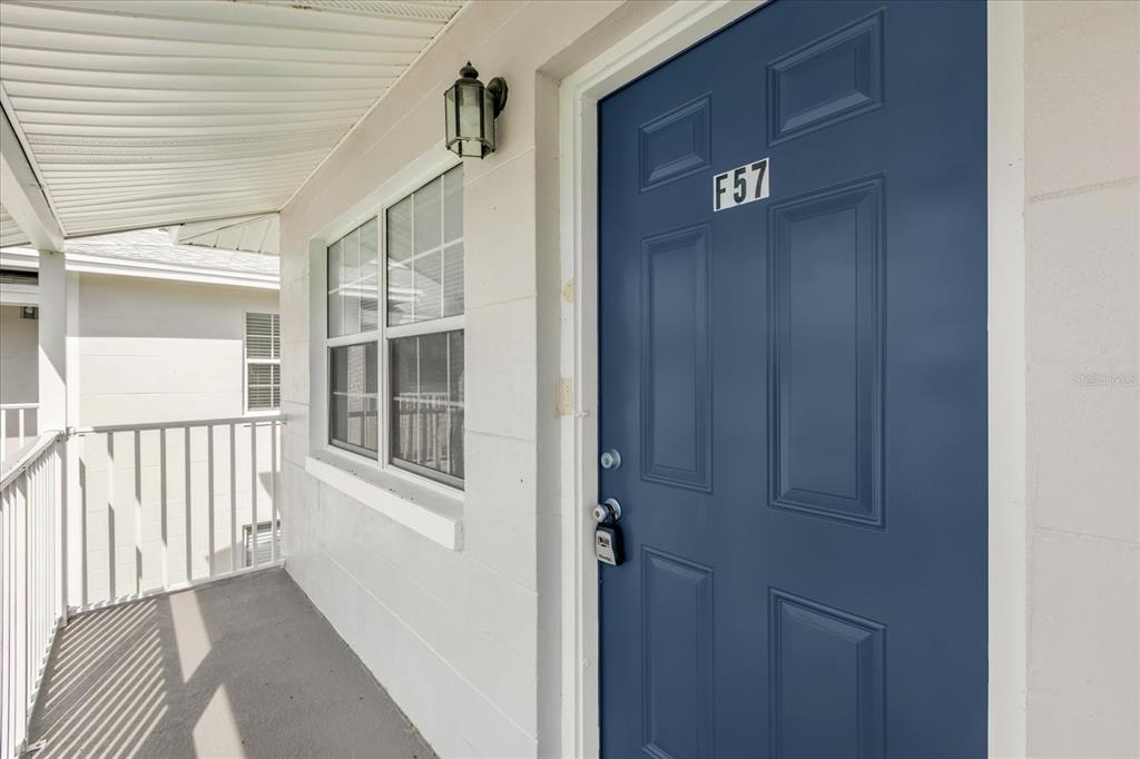 A blue front door labeled F57 is located on a covered exterior walkway — 1400 EUDORA RD UNIT F57, MOUNT DORA, FL