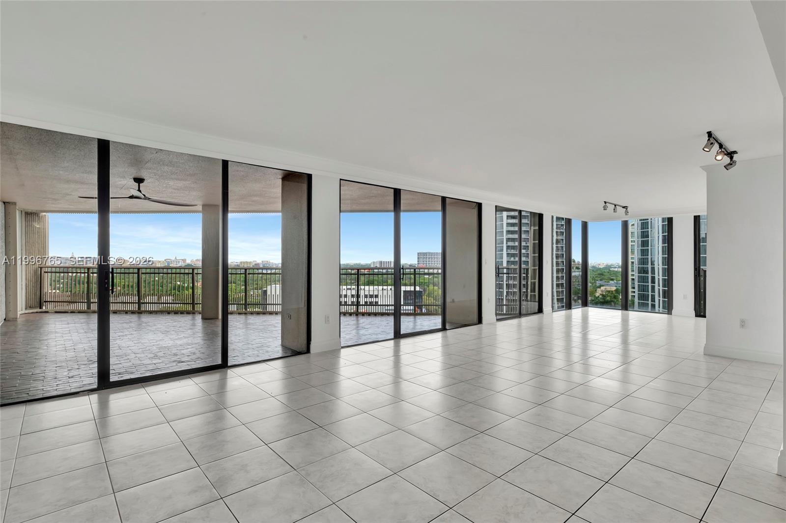 An empty room with white tile floors, large sliding glass doors, and a balcony view — 2901 S Bayshore Dr # 16G, Miami FL 33133, MIAMI, FL