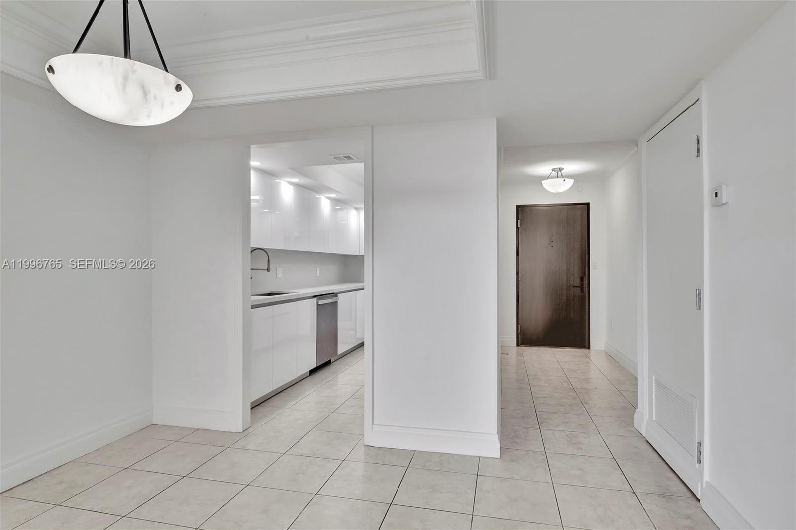 A white-tiled hallway leads to a dark door, with a modern kitchen visible to the left — 2901 S Bayshore Dr # 16G, Miami FL 33133, MIAMI, FL