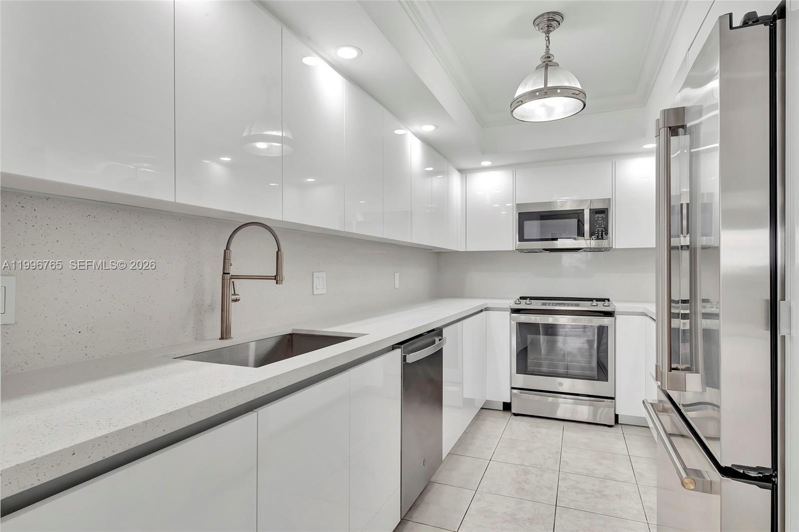 A modern galley kitchen features white high-gloss cabinets, stainless steel appliances, and light-colored countertops — 2901 S Bayshore Dr # 16G, Miami FL 33133, MIAMI, FL