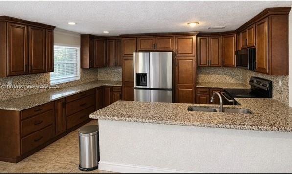 A kitchen features dark wood cabinets, granite countertops, and stainless steel appliances — 10207 SW 20th Ct, Miramar FL 33025, MIRAMAR, FL