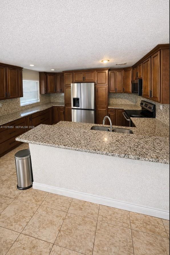 A kitchen features dark wood cabinets, granite countertops, stainless steel appliances, and tiled flooring — 10207 SW 20th Ct, Miramar FL 33025, MIRAMAR, FL