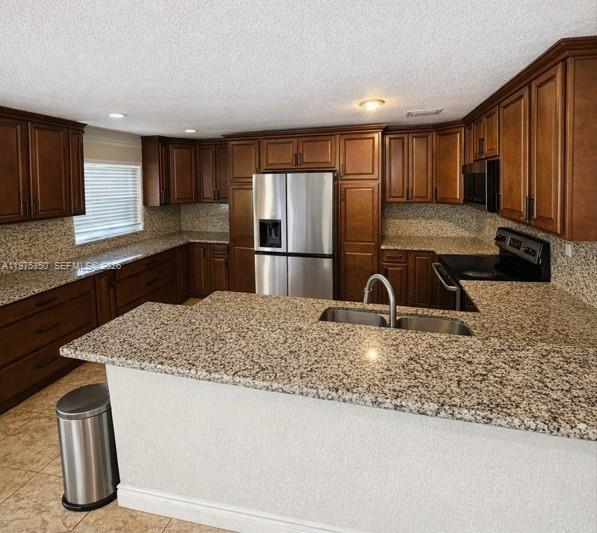 A kitchen features wood cabinets, granite countertops, stainless steel appliances, and a breakfast bar — 10207 SW 20th Ct, Miramar FL 33025, MIRAMAR, FL