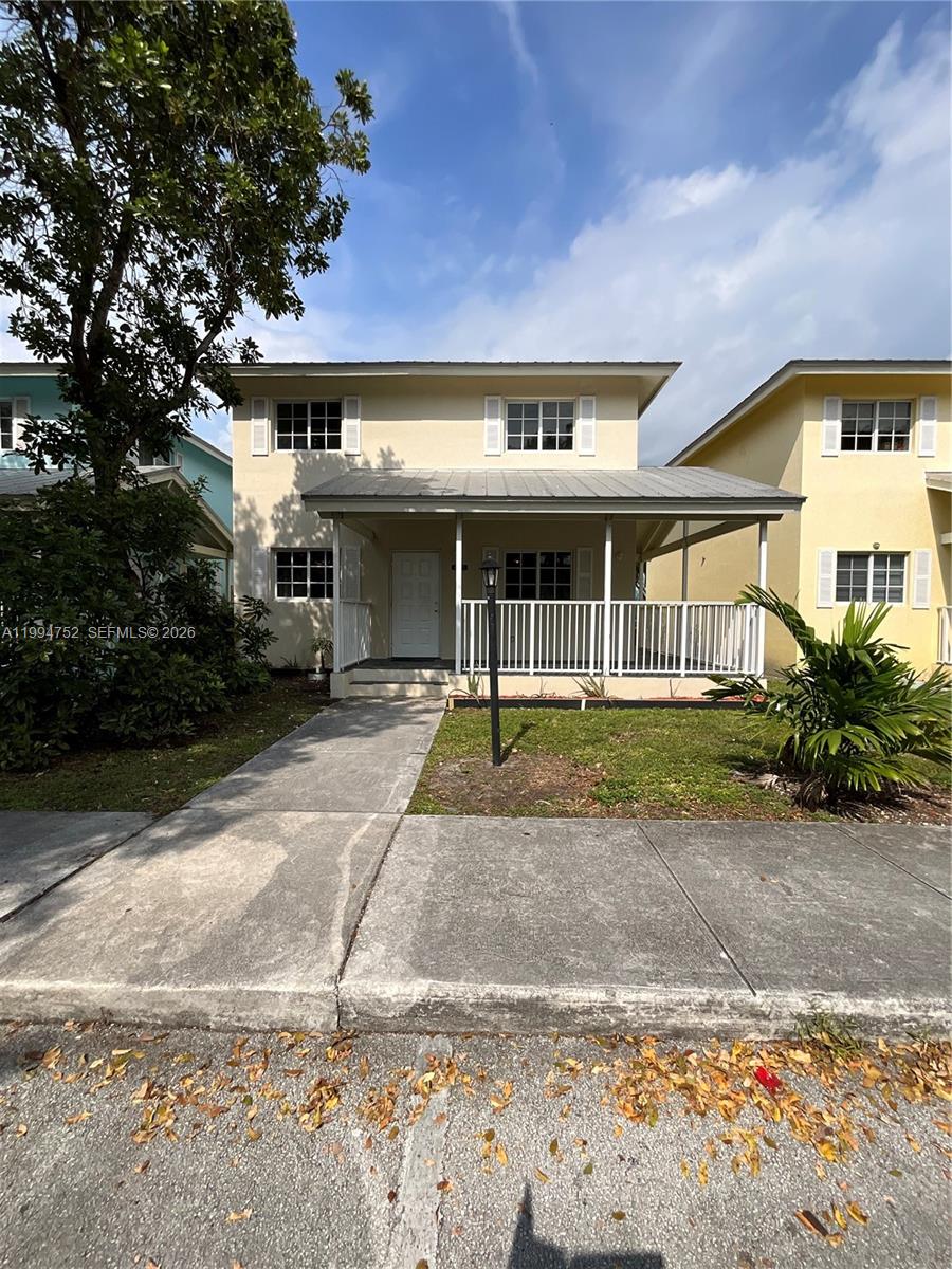 A two-story house with a covered front porch and white railings stands behind a sidewalk — 435 NW 19th Ln # 19, Miami FL 33136, MIAMI, FL