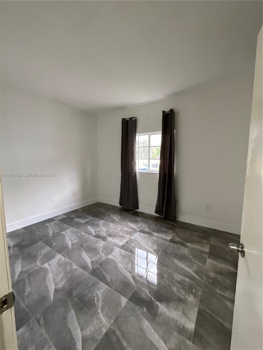 An empty bedroom features light gray walls, dark gray curtains, and large marble-patterned floor tiles — 435 NW 19th Ln # 19, Miami FL 33136, MIAMI, FL