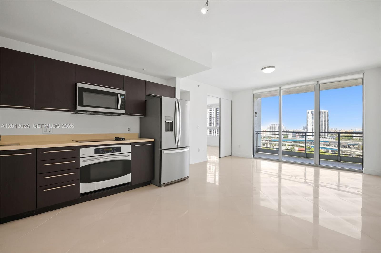 A modern kitchen with dark wood cabinets and stainless steel appliances opens to a balcony — 90 SW 3rd St # 1608, Miami FL 33130, MIAMI, FL