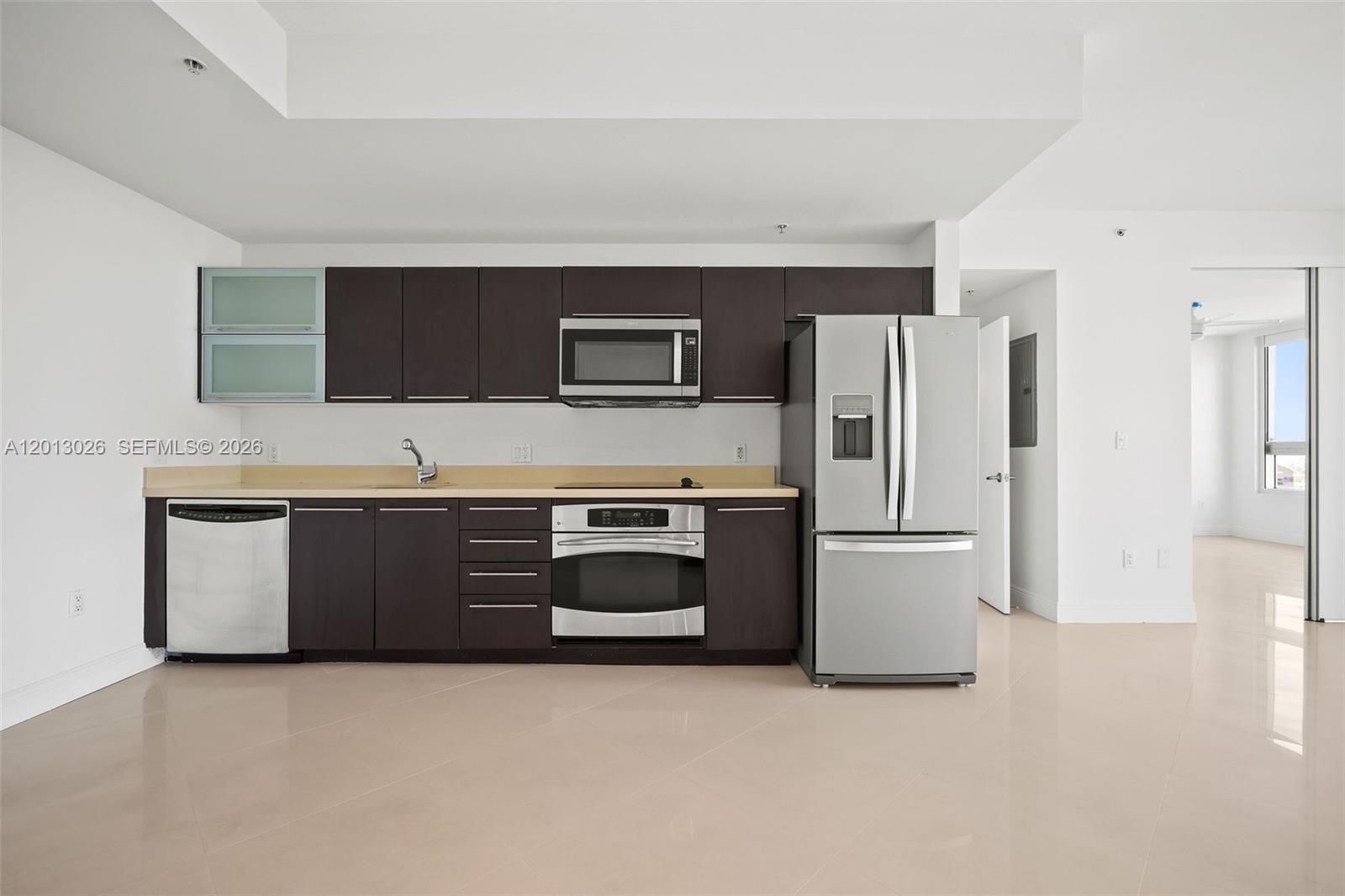 A kitchen features dark wood cabinets, stainless steel appliances, and light-colored countertops and flooring — 90 SW 3rd St # 1608, Miami FL 33130, MIAMI, FL