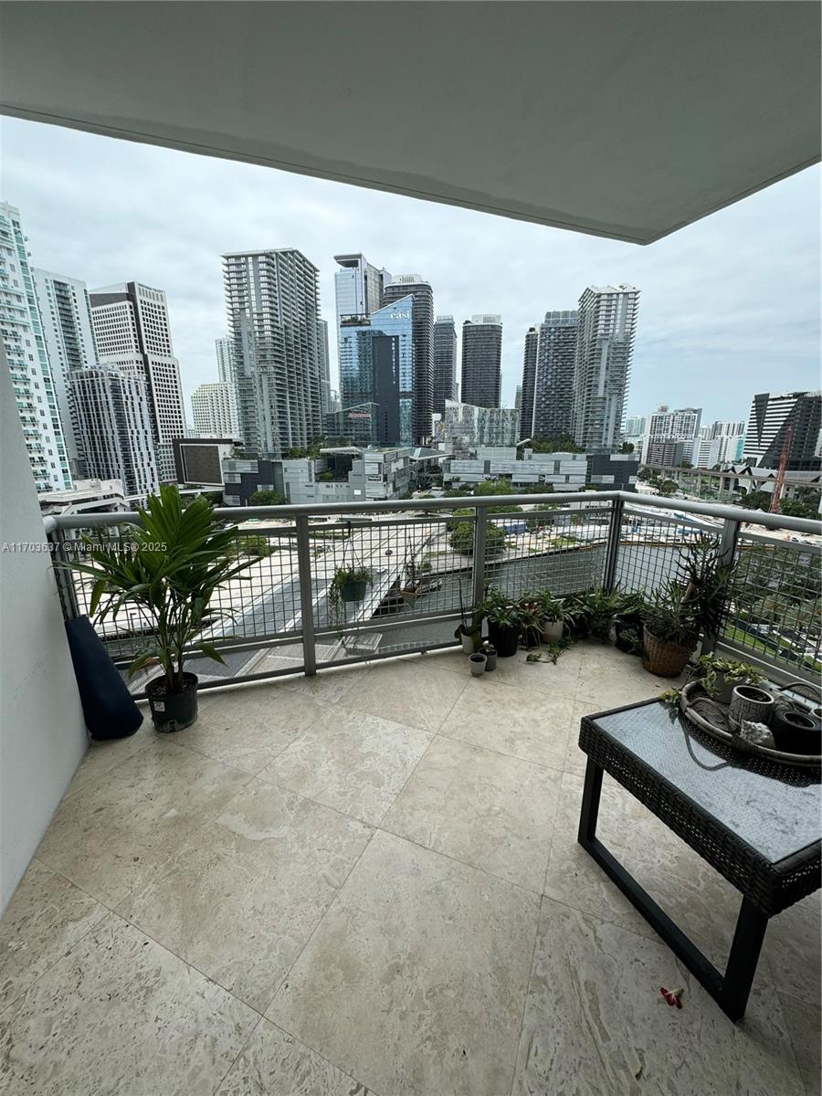 A balcony with stone flooring and potted plants overlooks a dense urban skyline — 350 S Miami Ave # 1704, Miami FL 33130, MIAMI, FL