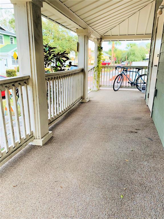 A covered porch features a textured concrete floor, white wooden railings, and a parked bicycle — 432 8TH AVENUE N UNIT 2, ST PETERSBURG, FL