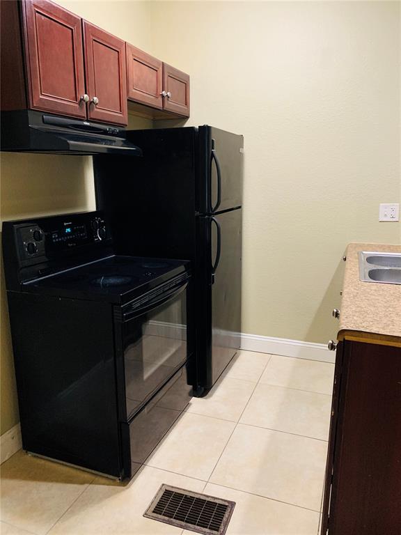 A kitchen features dark wood cabinets, black appliances, a stove, and light-colored tile flooring — 432 8TH AVENUE N UNIT 2, ST PETERSBURG, FL