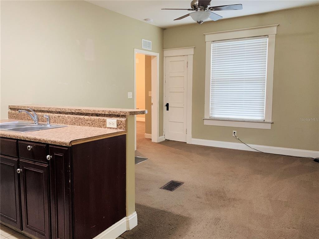 A kitchen counter with a sink overlooks a carpeted room with a door and window — 432 8TH AVENUE N UNIT 2, ST PETERSBURG, FL