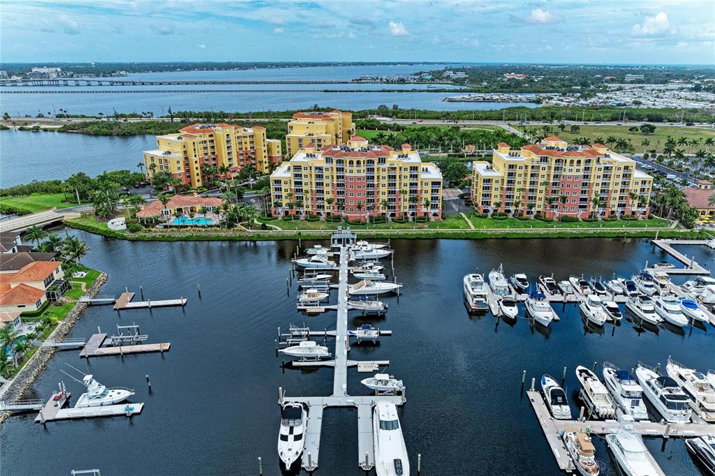 An aerial view shows a marina with docked boats in front of several large apartment buildings — 610 RIVIERA DUNES WAY UNIT 404, PALMETTO, FL
