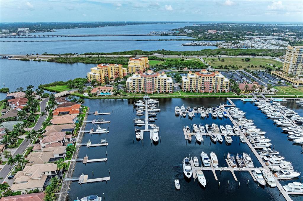 An aerial view of a marina with many boats docked near residential buildings and water — 610 RIVIERA DUNES WAY UNIT 404, PALMETTO, FL