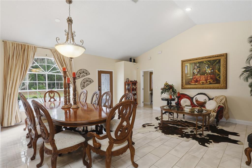 A dining room with a wooden table, ornate chairs, a chandelier, and a cowhide rug — 1898 BLACKWELDER ROAD, DE LEON SPRINGS, FL
