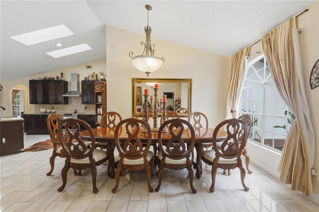 A dining room features a wooden table with six chairs, a chandelier, and tiled floors — 1898 BLACKWELDER ROAD, DE LEON SPRINGS, FL