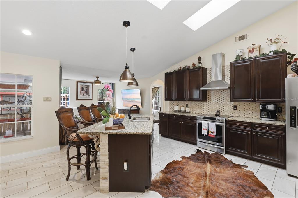A kitchen with dark wood cabinets, granite countertops, a center island, and a cowhide rug — 1898 BLACKWELDER ROAD, DE LEON SPRINGS, FL