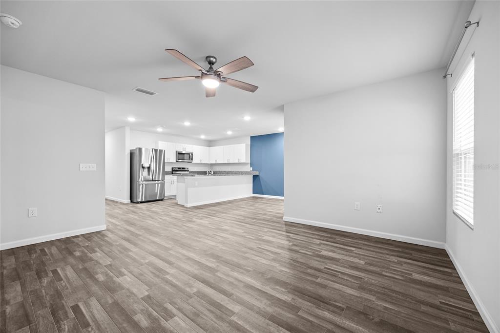 An open-concept living area with wood-look flooring leads to a kitchen with white cabinets — 20105 NW 247TH STREET, HIGH SPRINGS, FL