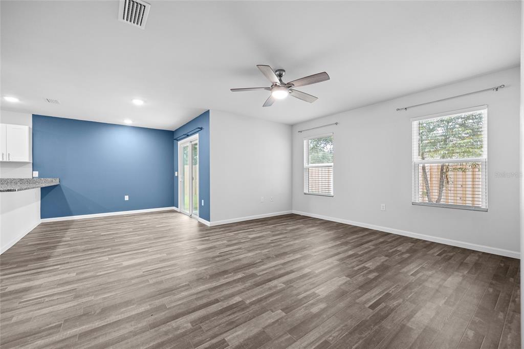 An open-concept living area features gray wood-look flooring, a blue accent wall, and sliding doors — 20105 NW 247TH STREET, HIGH SPRINGS, FL