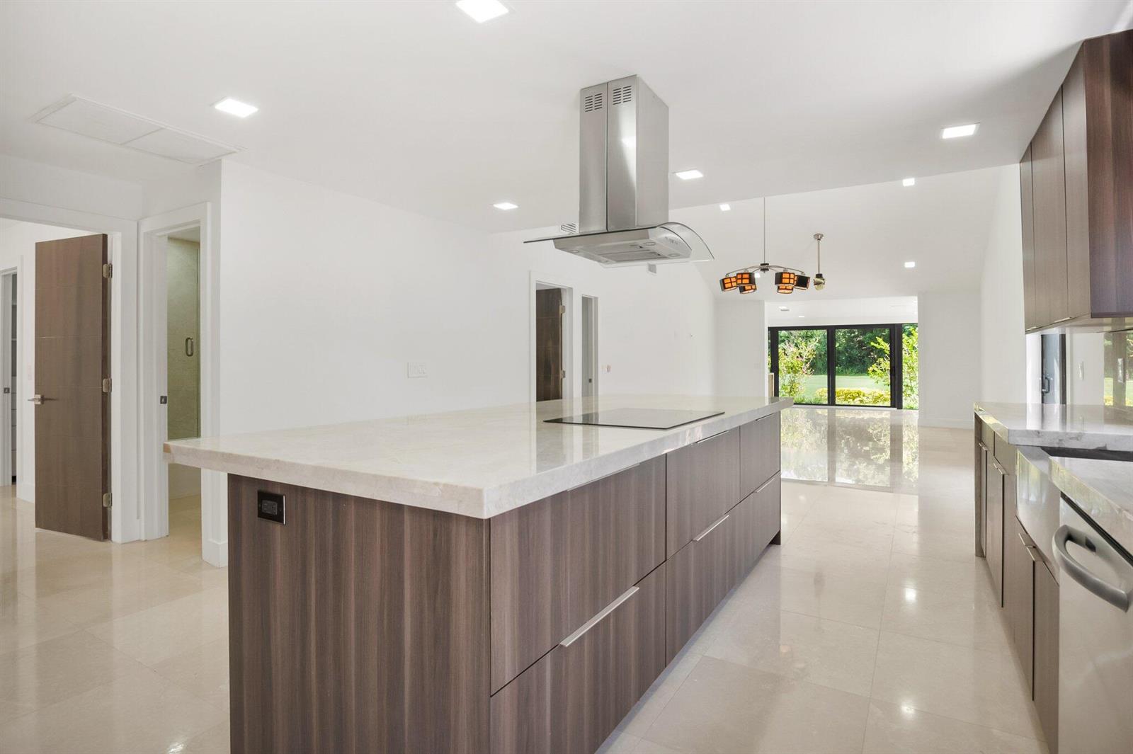 A modern kitchen features a large wood-toned island with a cooktop and white stone countertops — 21922 Cypress Drive, Boca Raton FL 33433, BOCA RATON, FL