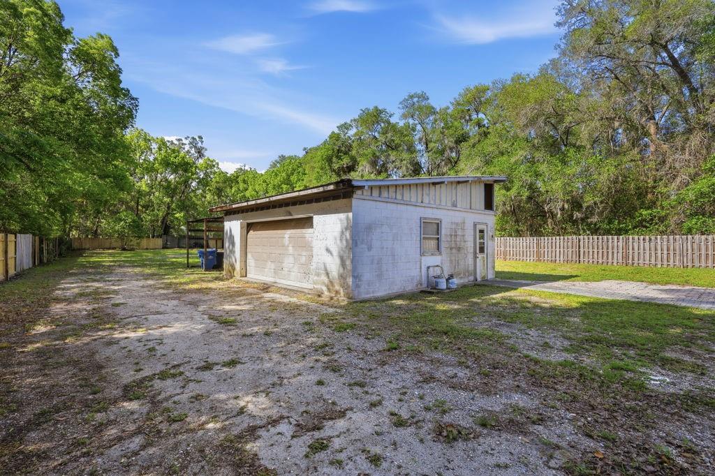 A detached concrete block garage sits on a large, grassy lot with a gravel driveway — 550 E MINNESOTA AVENUE, ORANGE CITY, FL