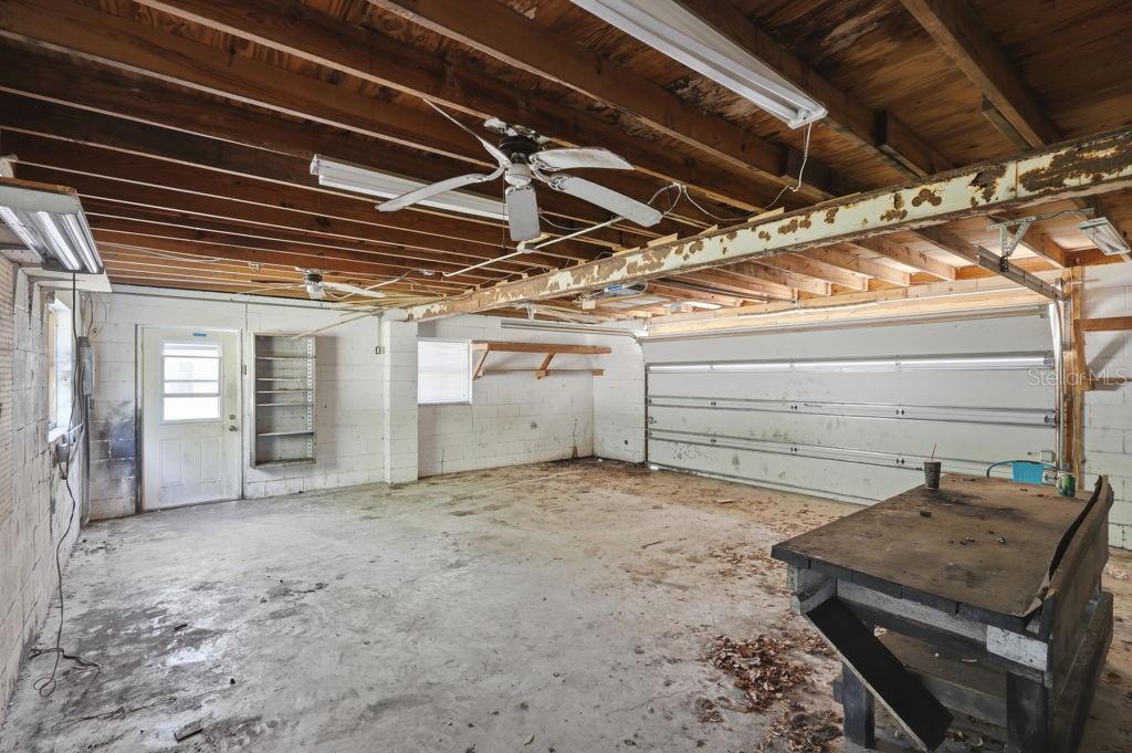 An unfinished garage with a concrete floor, exposed wooden ceiling joists, and a workbench — 550 E MINNESOTA AVENUE, ORANGE CITY, FL