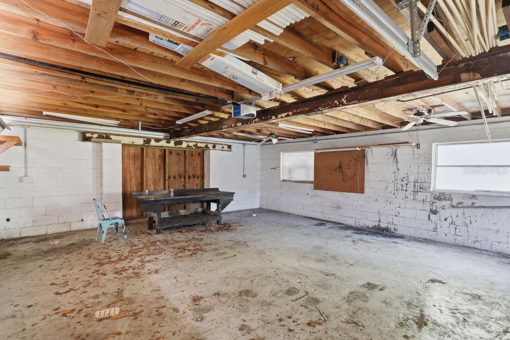 An unfinished garage with exposed wooden ceiling joists, concrete block walls, and a workbench — 550 E MINNESOTA AVENUE, ORANGE CITY, FL