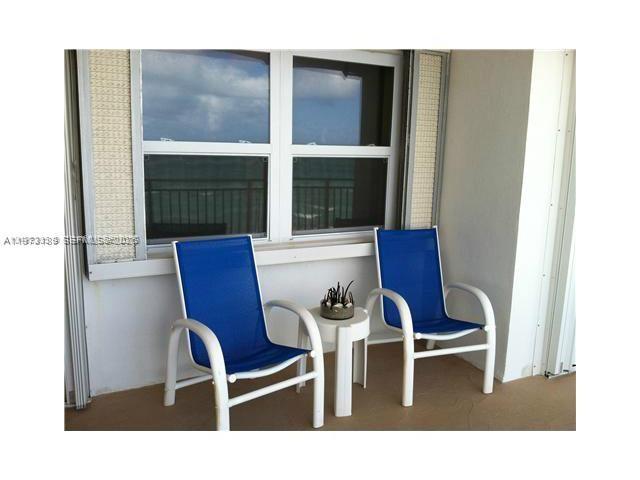 Two blue patio chairs and a small side table sit on a balcony overlooking water — 901 S Surf Rd # 402, Hollywood FL 33019, HOLLYWOOD, FL