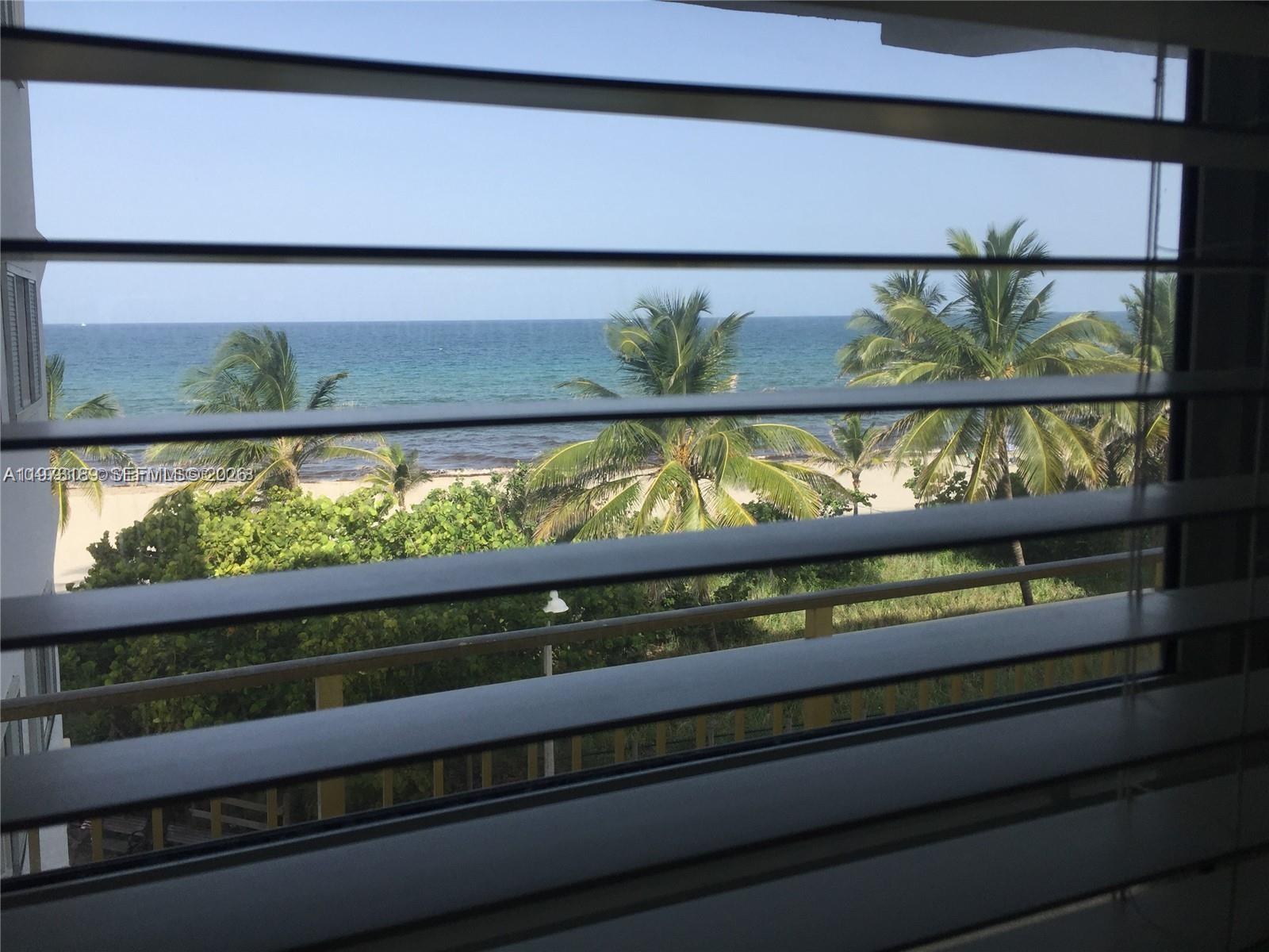 A view of the beach and ocean through horizontal window blinds — 901 S Surf Rd # 402, Hollywood FL 33019, HOLLYWOOD, FL