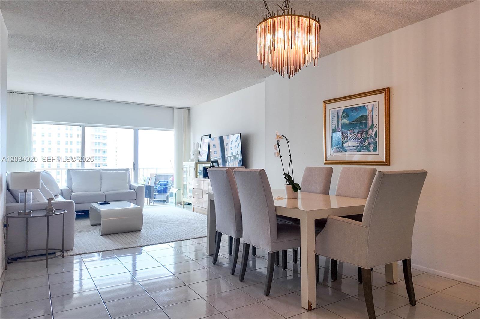 A dining area with a chandelier and a living room with a balcony view — 1950 S Ocean Dr # 5B, Hallandale Beach FL 33009, HALLANDALE BEACH, FL