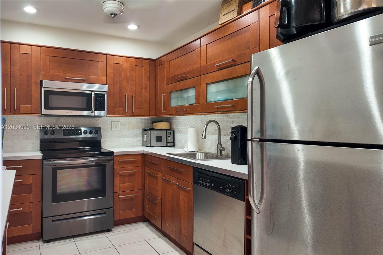 A kitchen features wood cabinets, stainless steel appliances, and a light-colored tiled backsplash — 1950 S Ocean Dr # 5B, Hallandale Beach FL 33009, HALLANDALE BEACH, FL