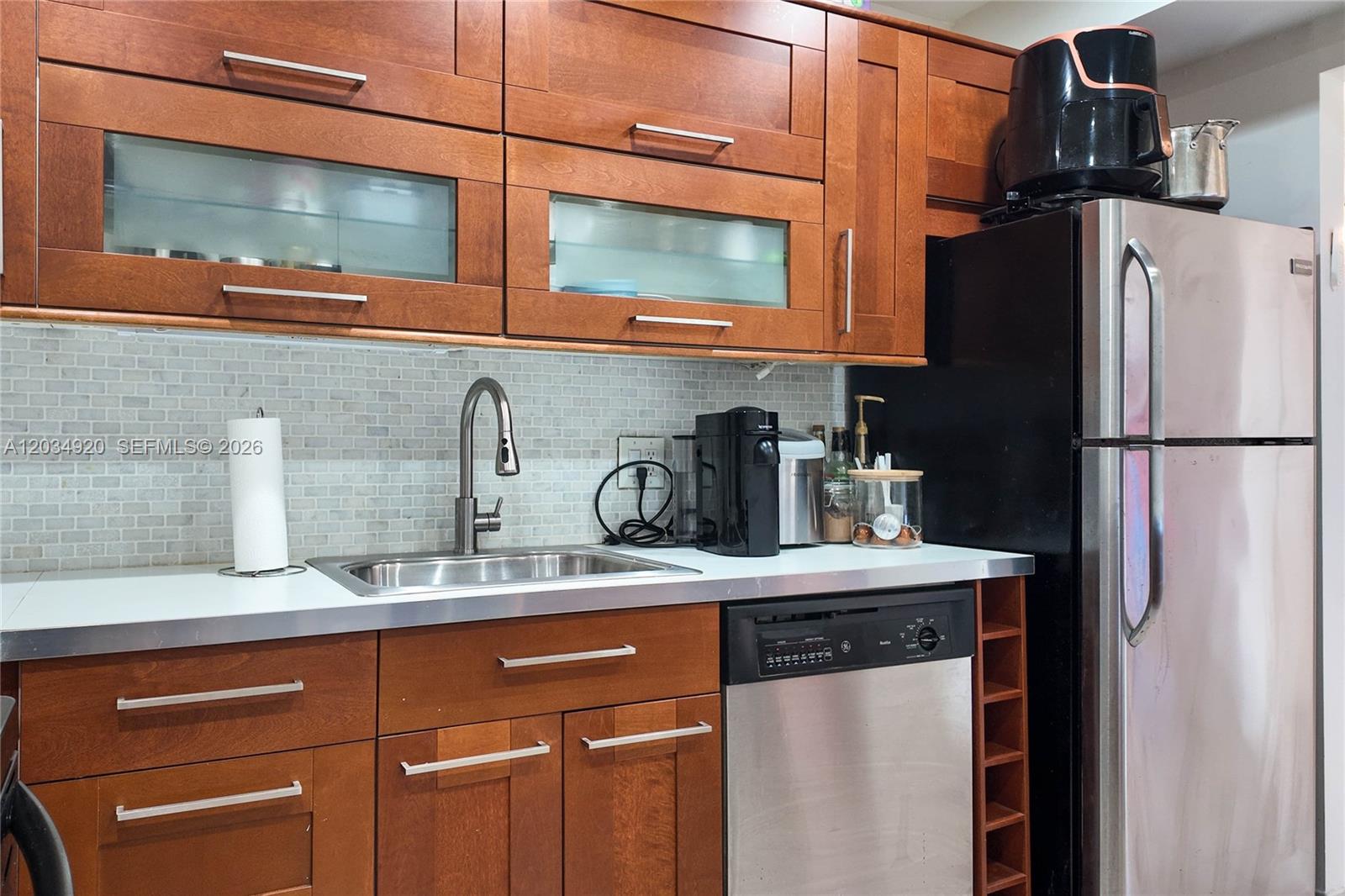 A kitchen features wood cabinets, stainless steel appliances, a sink, and a tiled backsplash — 1950 S Ocean Dr # 5B, Hallandale Beach FL 33009, HALLANDALE BEACH, FL