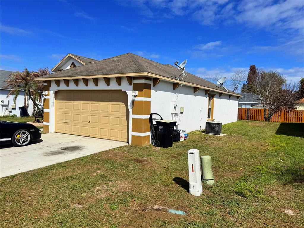 A detached garage with a tan door, white stucco walls, and brown corner accents — 3661 QUEENS COVE BOULEVARD, WINTER HAVEN, FL