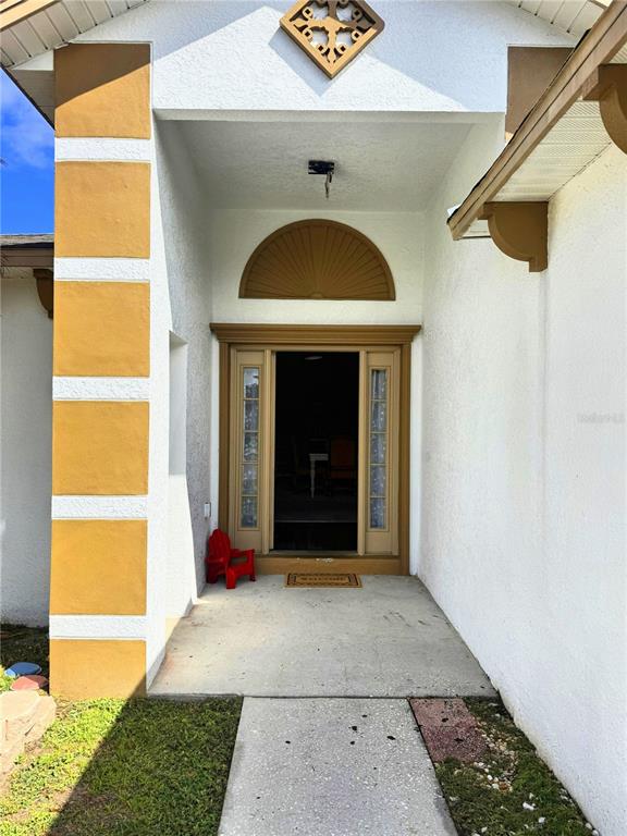The exterior entryway features a tan-trimmed door with a fanlight window and a small chair — 3661 QUEENS COVE BOULEVARD, WINTER HAVEN, FL