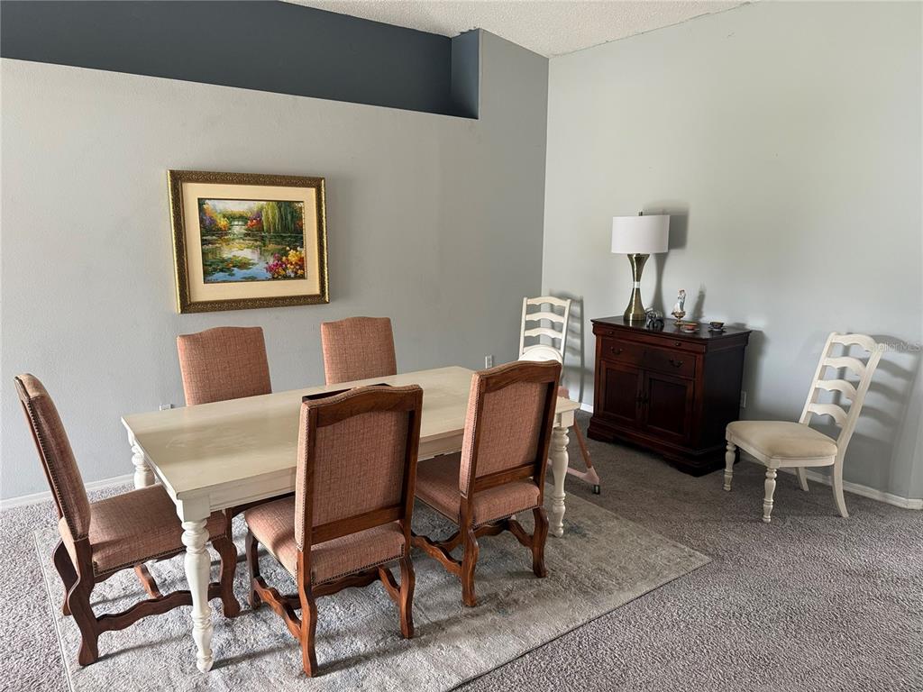 A dining room features a light-colored table with six chairs, a dark wood cabinet, and artwork — 3661 QUEENS COVE BOULEVARD, WINTER HAVEN, FL