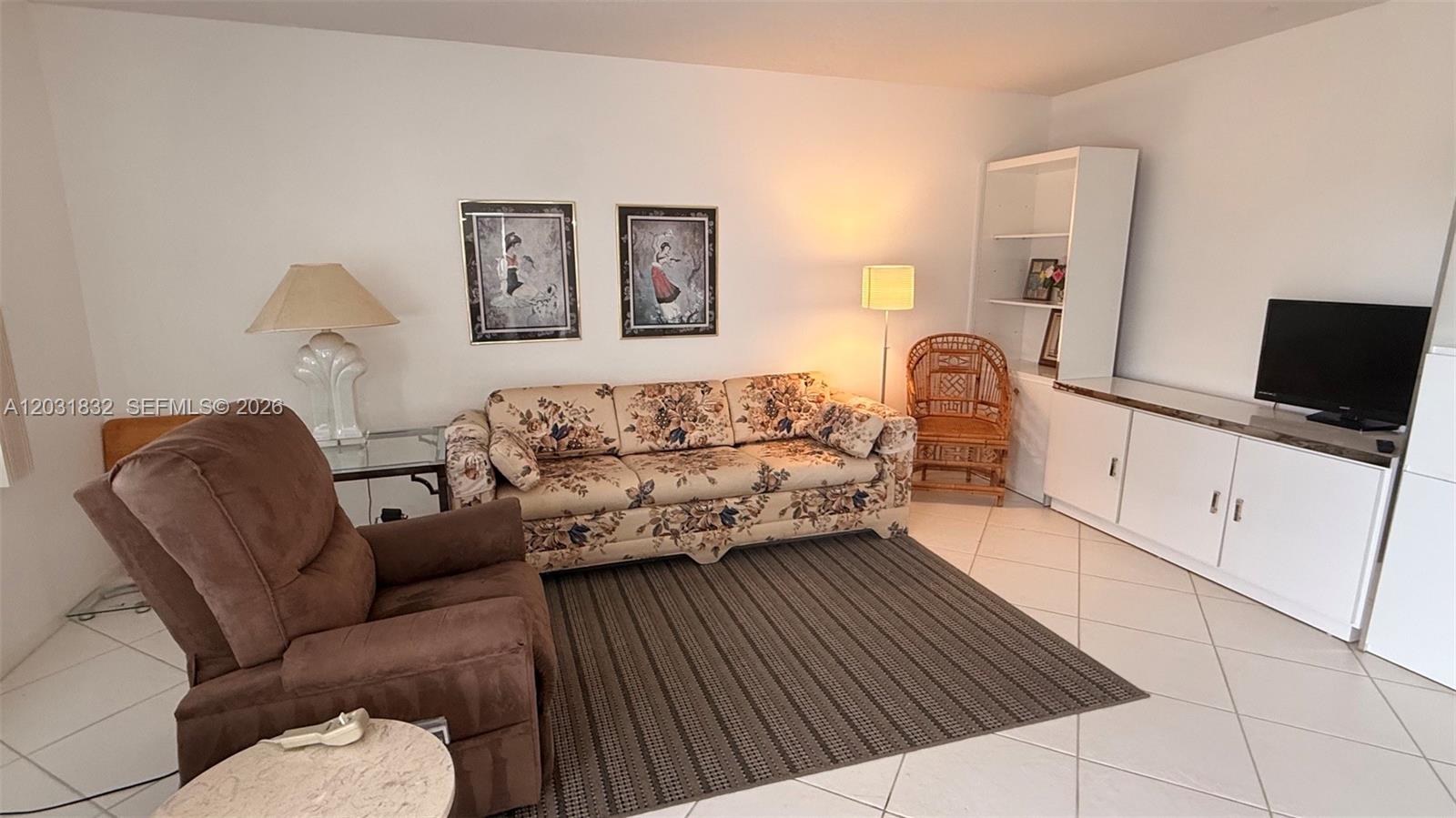 A living room features a floral sofa, a brown recliner, and white built-in cabinetry — 322 Piedmont G # G, Delray Beach FL 33484, DELRAY BEACH, FL