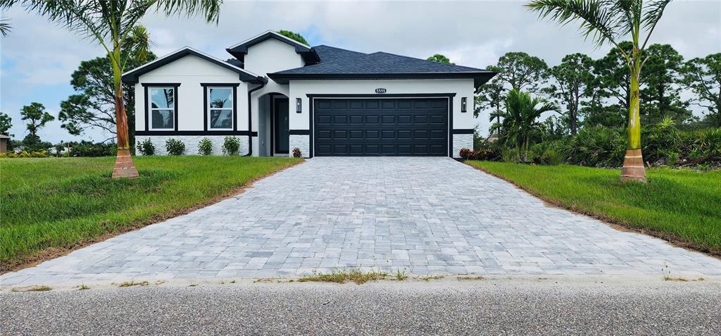 A single-story house with a white exterior, black trim, and a paved driveway — 5555 VERACRUZ TERRACE, PORT CHARLOTTE, FL