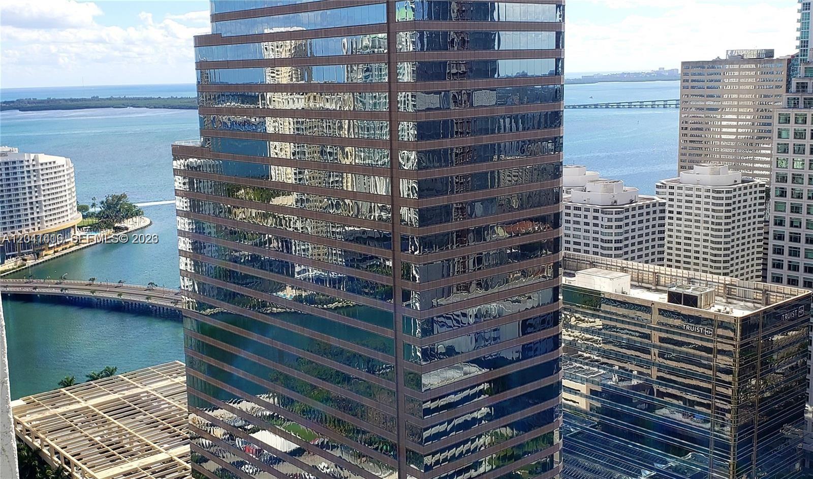 An elevated exterior view of a glass-clad skyscraper overlooking a bay and city buildings — 500 Brickell Ave # 3706, Miami FL 33131, MIAMI, FL