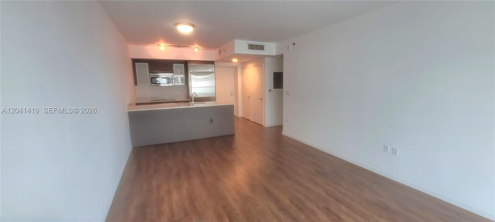 An open-concept living area features wood-look flooring and a kitchen with stainless steel appliances — 500 Brickell Ave # 3706, Miami FL 33131, MIAMI, FL