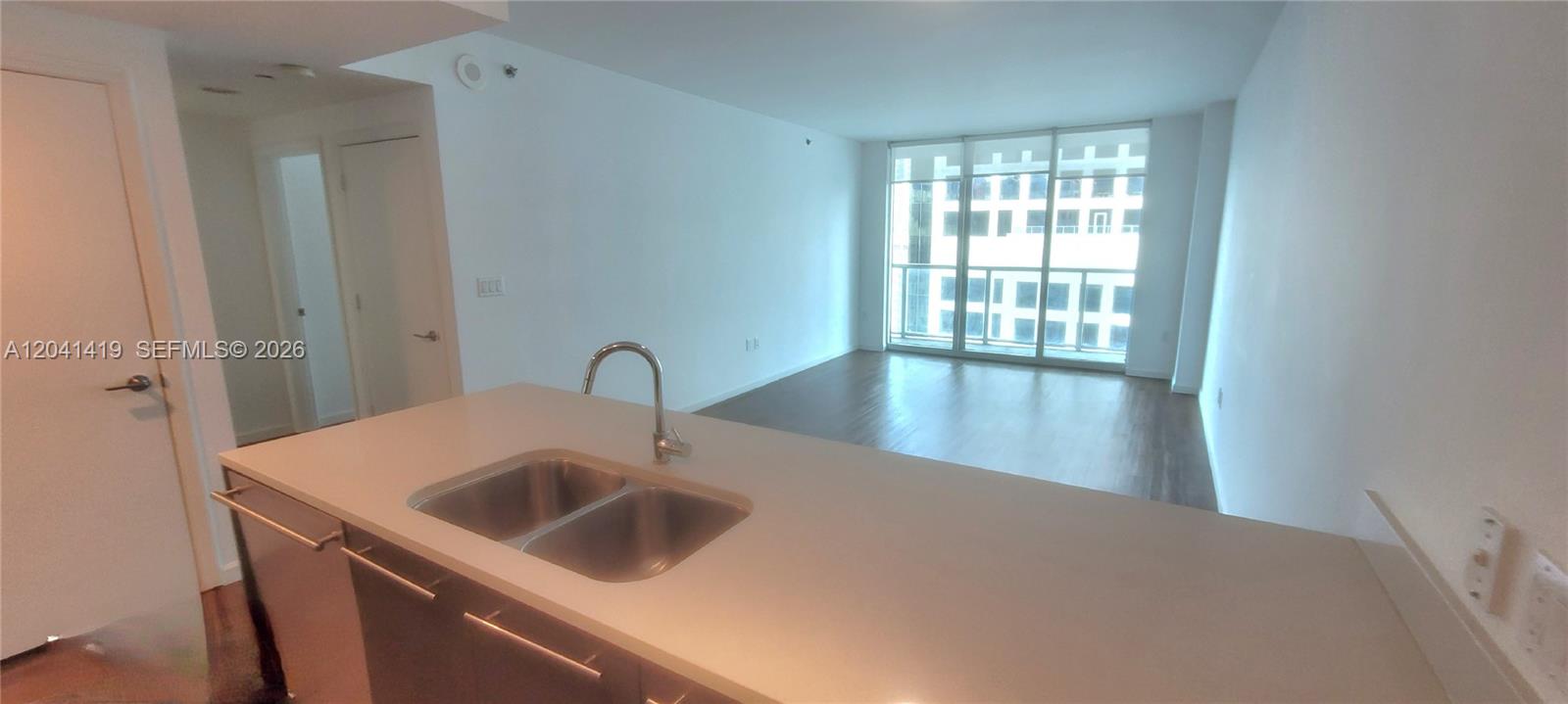 A kitchen island with a double sink overlooks an open living area with floor-to-ceiling windows — 500 Brickell Ave # 3706, Miami FL 33131, MIAMI, FL