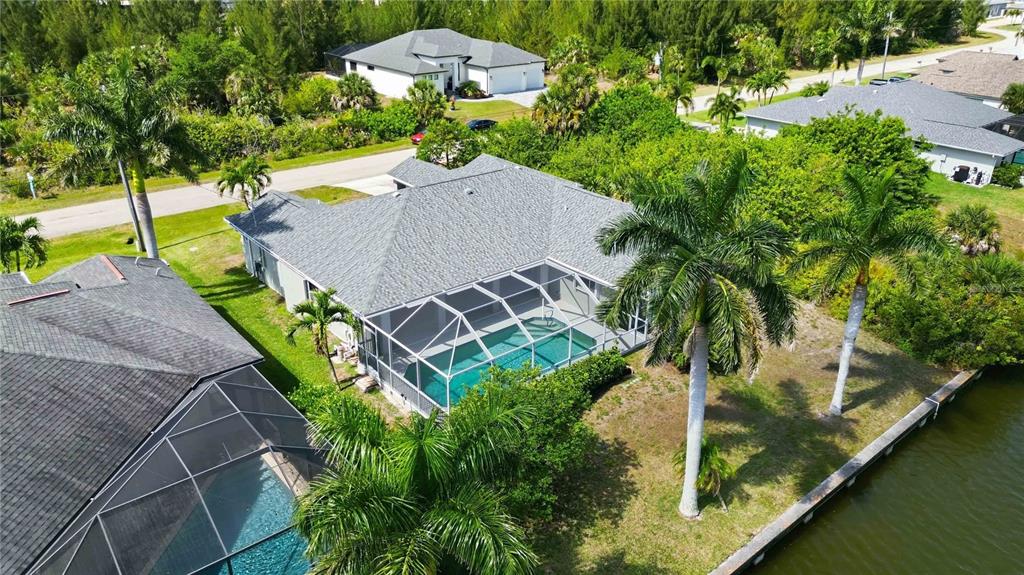 An aerial view of a house with a screened-in pool and palm trees by a canal — 15608 MELPORT CIRCLE, PORT CHARLOTTE, FL