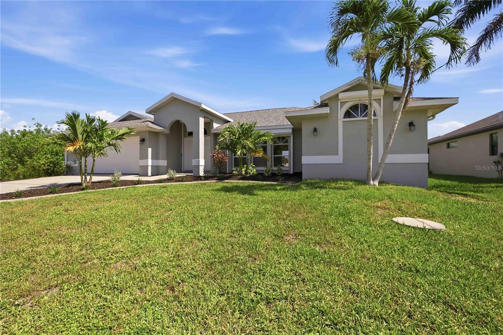 A single-story house with a gray stucco exterior, a shingled roof, and palm trees — 15608 MELPORT CIRCLE, PORT CHARLOTTE, FL