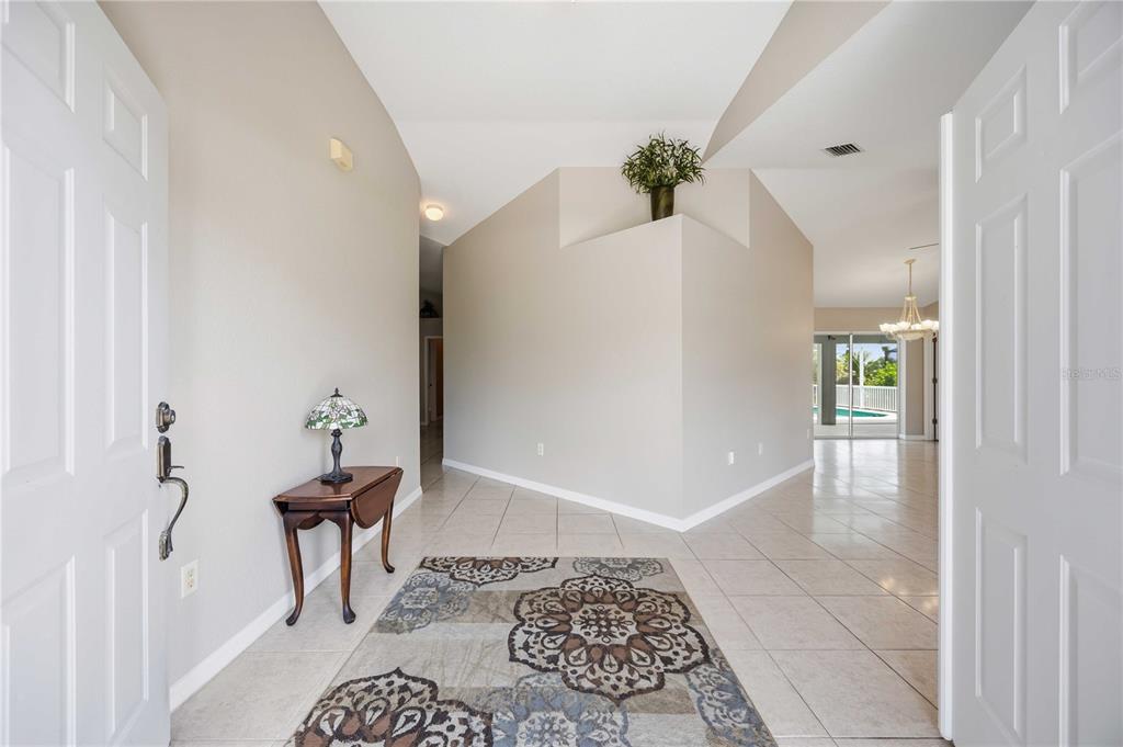 A tiled entryway features a small wooden table, a patterned rug, and a central wall — 15608 MELPORT CIRCLE, PORT CHARLOTTE, FL