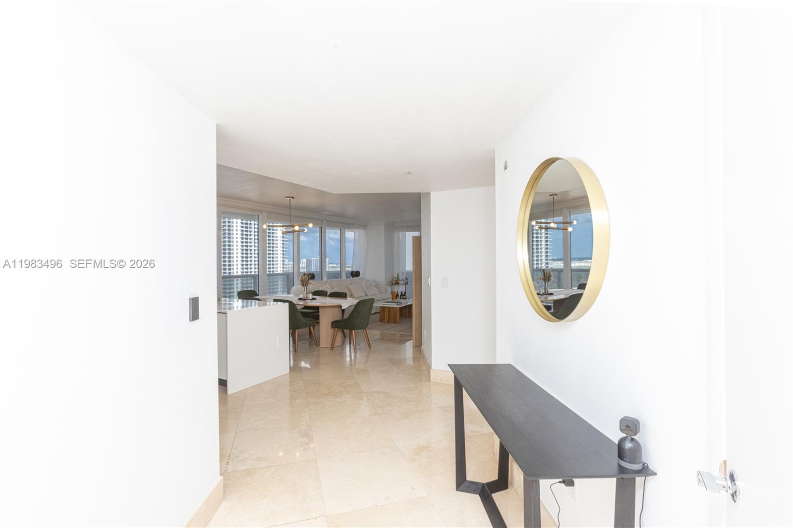 A hallway with a console table and mirror leads into an open-concept dining and living area — 1830 S Ocean Dr # 2108, Hallandale Beach FL 33009, HALLANDALE BEACH, FL