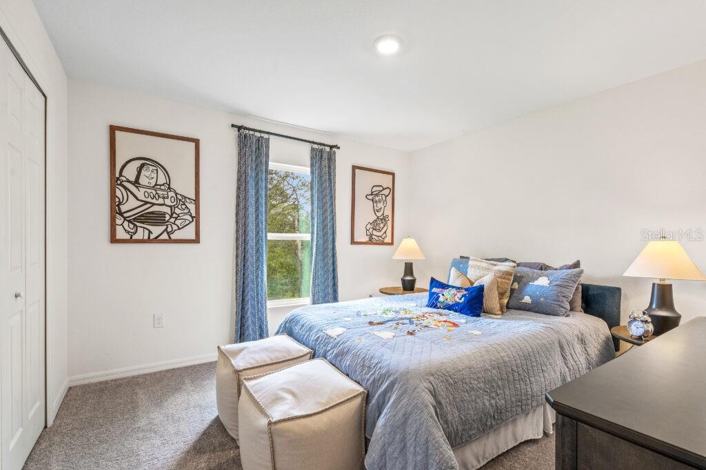 A bedroom features a bed with blue bedding, two Toy Story wall prints, and two ottomans — 444 PATRICIA ALFORD DRIVE, HAINES CITY, FL